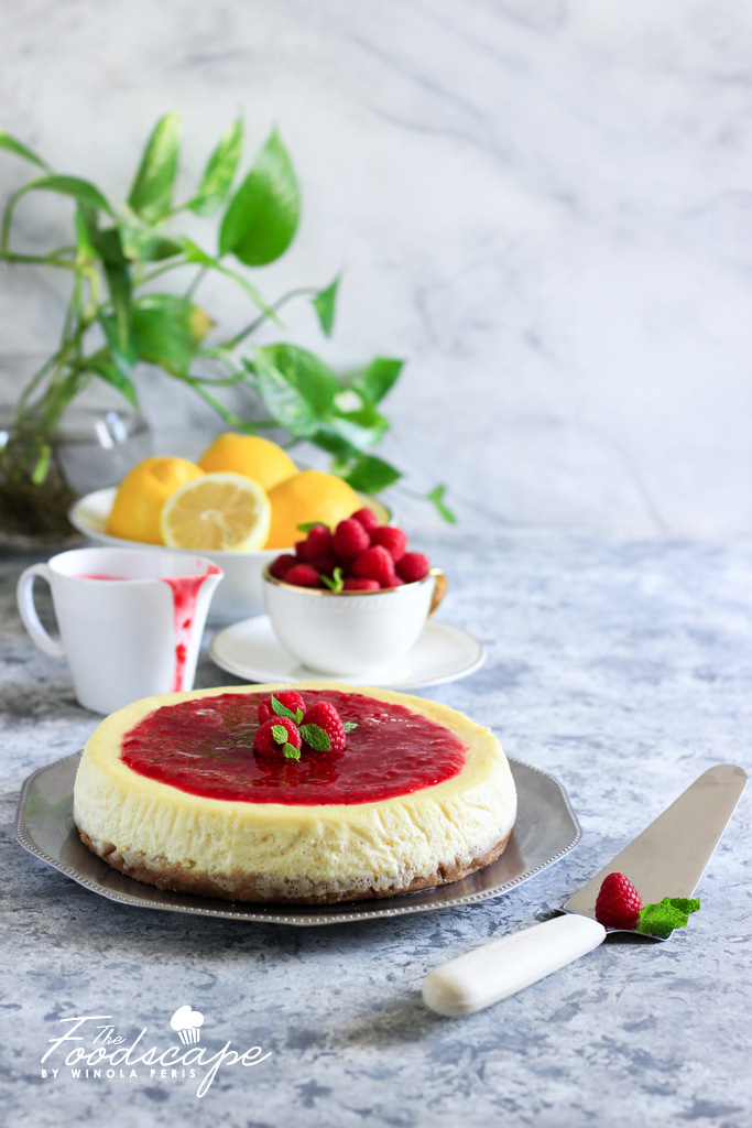 A lush, creamy Baked Lemon Cheesecake topped with a tangy and delicious Raspberry Sauce. A beautiful Spring/Summer Dessert, Lemon Dessert recipe, that is sure to be among your favourites! Cheesecake Recipe. Food Photography